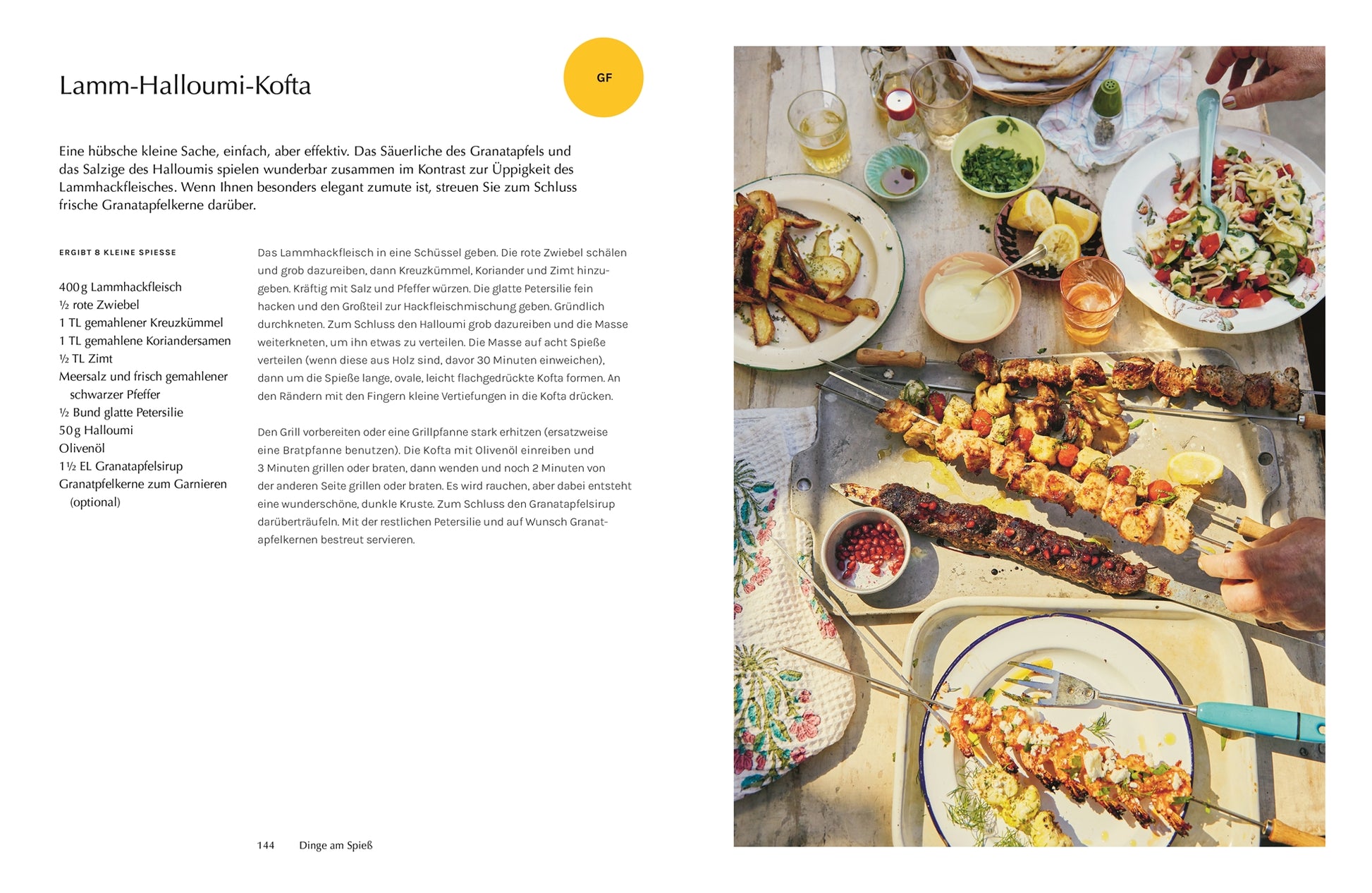 Lamm-Halloumi-Kofta: Grillteller mit verschiedenen Fleischspießen, Halloumi und Granatapfel, dazu Salat, Kartoffelspalten und Dips auf einem sommerlich gedeckten Tisch.