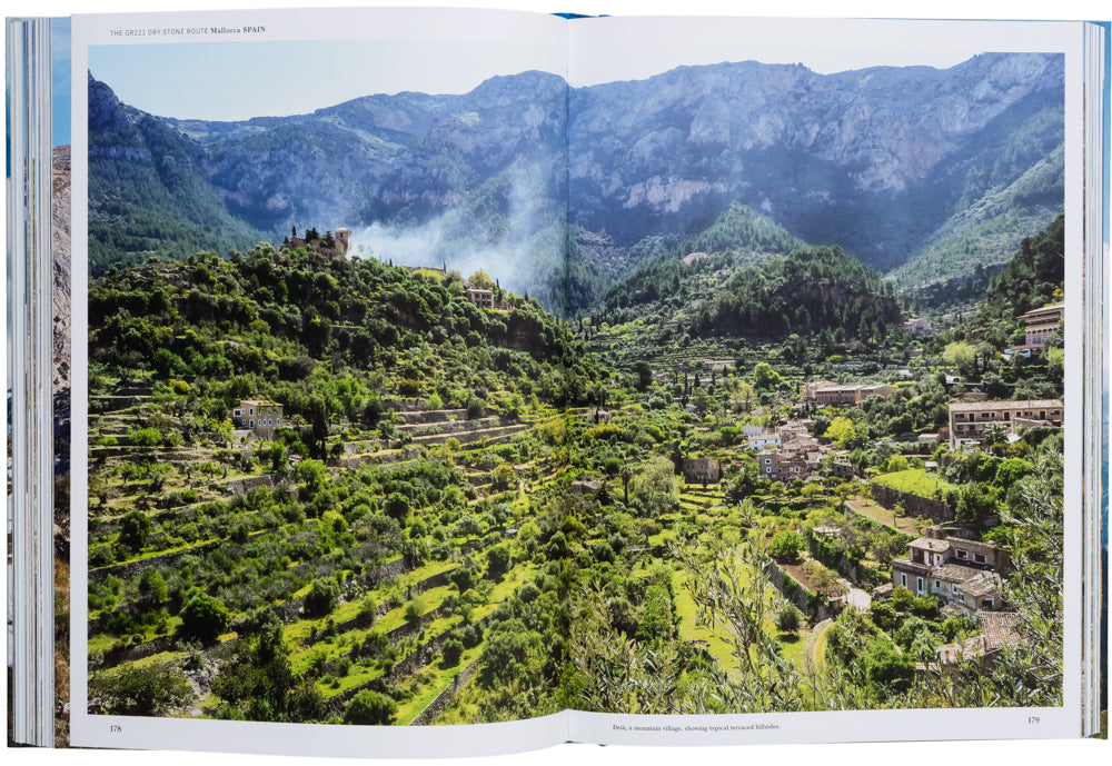 Doppelseite aus dem Buch Wanderlust Europe: Blick auf das Bergdorf Deià auf Mallorca entlang der GR221 Trockenmauerroute mit typischen Terrassenfeldern und der Serra-de-Tramuntana im Hintergrund.