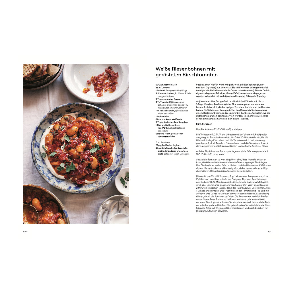 Weiße Riesenbohnen mit gerösteten Kirschtomaten: Schmortopf mit weißen Riesenbohnen in einer würzigen Tomatensauce auf Joghurt, dekoriert mit frischen Oreganoblättern, umgeben von leeren Schalen und angeröstetem Brot.