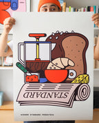 Fine Art Print Wiener Standard Frühstück von RadandYellow aus Wien wird in Händen gehalten und zeigt eine farbenfrohe Illustration eines klassischen Wiener Frühstücks mit Croissant, Brot, Käse, Marmelade, Kaffeepresse und Zeitung. Der limitierte Kunstdruck verbindet Pop-Art mit österreichischer Frühstückskultur und bringt spielerische Leichtigkeit in moderne Wohnräume.
