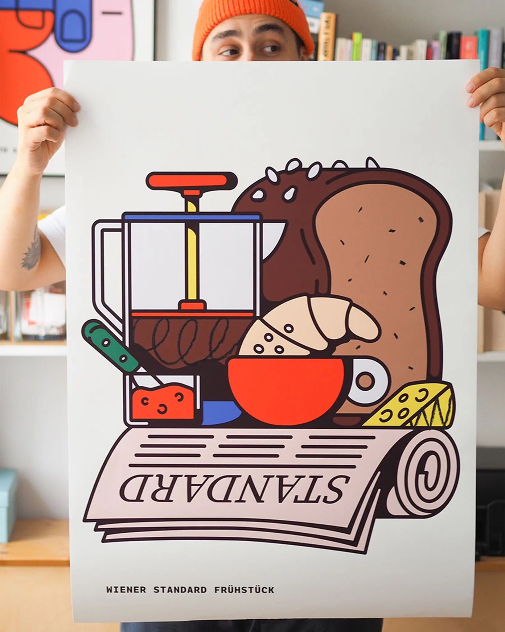 Fine Art Print Wiener Standard Frühstück von RadandYellow aus Wien wird in Händen gehalten und zeigt eine farbenfrohe Illustration eines klassischen Wiener Frühstücks mit Croissant, Brot, Käse, Marmelade, Kaffeepresse und Zeitung. Der limitierte Kunstdruck verbindet Pop-Art mit österreichischer Frühstückskultur und bringt spielerische Leichtigkeit in moderne Wohnräume.