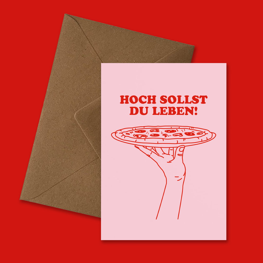 Geburtstagskarte „Hoch sollst du leben!“ mit rosa Vorderseite, roter Pizza Illustration und braunem nachhaltigem Briefumschlag, humorvolle Pizza Geburtstagskarte für Kinder und Erwachsene von studio ciao.