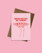 Geburtstagskarte „Hoch sollst du leben!“ mit rosa Vorderseite, roter Pizza Illustration und braunem nachhaltigem Briefumschlag, humorvolle Pizza Geburtstagskarte für Kinder und Erwachsene von studio ciao.