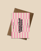 Moderne Geburtstagskarte ‚Ungefähr Dreissig‘ mit grafischem Streifenmuster in Pink und Beige, schwarzer Typografie und Aufschrift ‚Happy Birthday‘ und ‚Alles Gute‘, präsentiert mit braunem recyceltem Kraftpapier-Umschlag produziert in Deutschland
