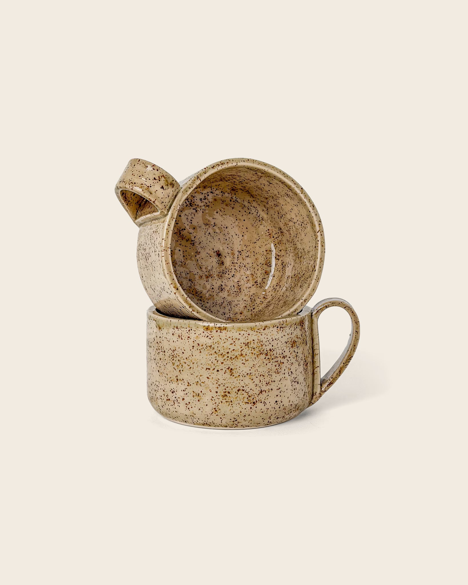 Handgefertigte Keramiktasse Caliente von Üm Studio in warmem Beige mit feinen braunen Sprenkeln. Große Steingut-Tasse mit ergonomischem Henkel, liebevoll gefertigt in Málaga, Spanien. Perfekt für Tee, Cappuccino oder achtsame Morgenrituale.