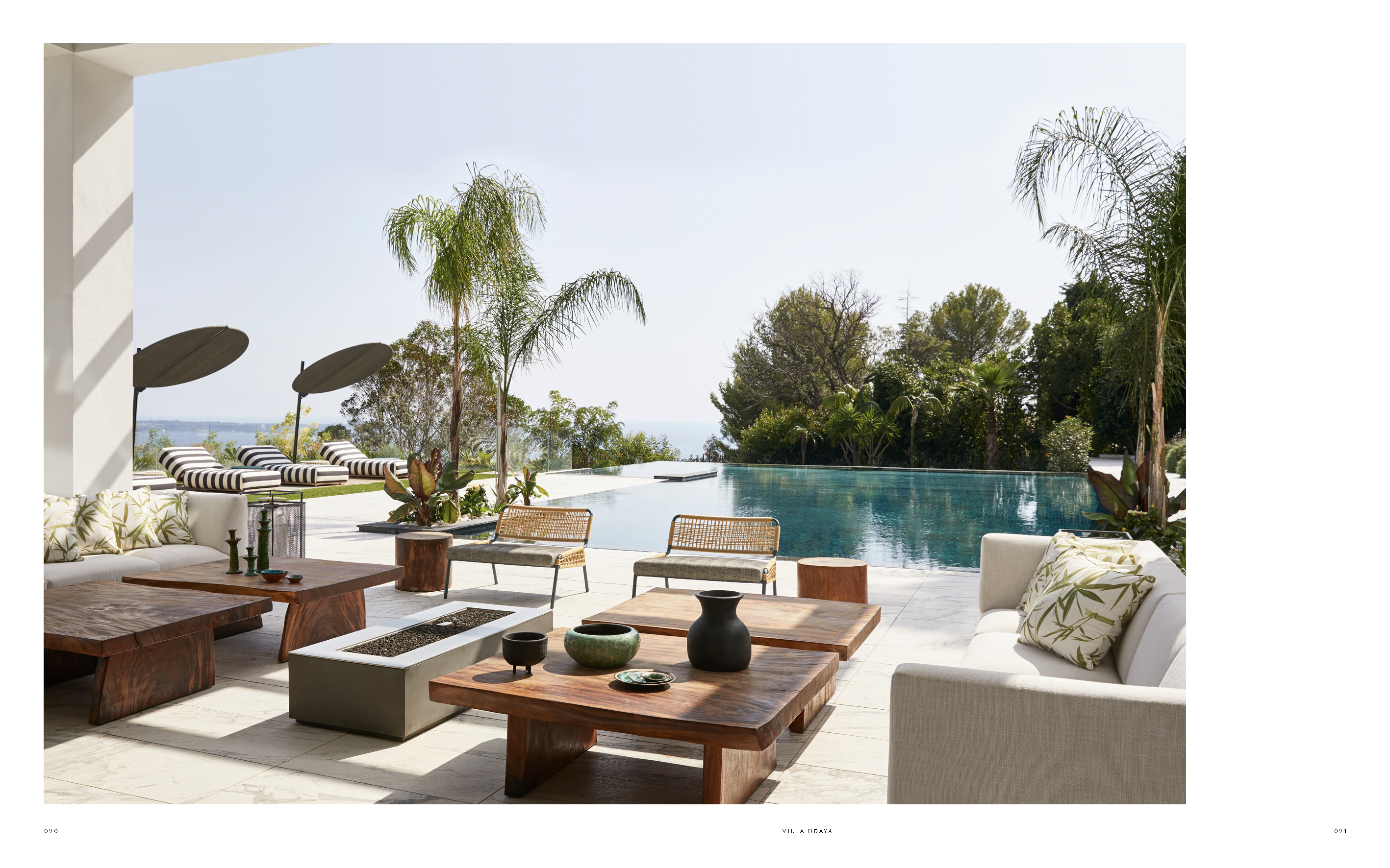 Luxuriöse Terrasse einer mediterranen Villa mit Infinity-Pool, Design-Holztischen, Rattanmöbeln und Palmenblick. Outdoor Living im modernen Côte-d’Azur-Stil.
