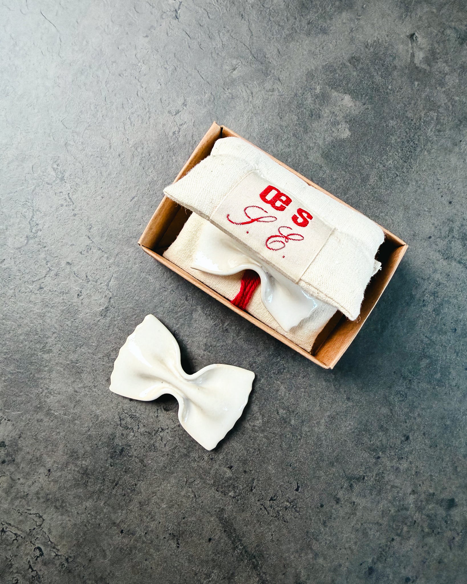 Handgefertigte Messerablage LA FARFALLE aus Keramik von OEUVRES SENSIBLES mit Verpackung. Inspiriert von italienischer Farfalle-Pasta, glänzende Glasur in Farbe Grès Shinny, gefertigt in Marseille. Elegantes Tischaccessoire aus Frankreich. 