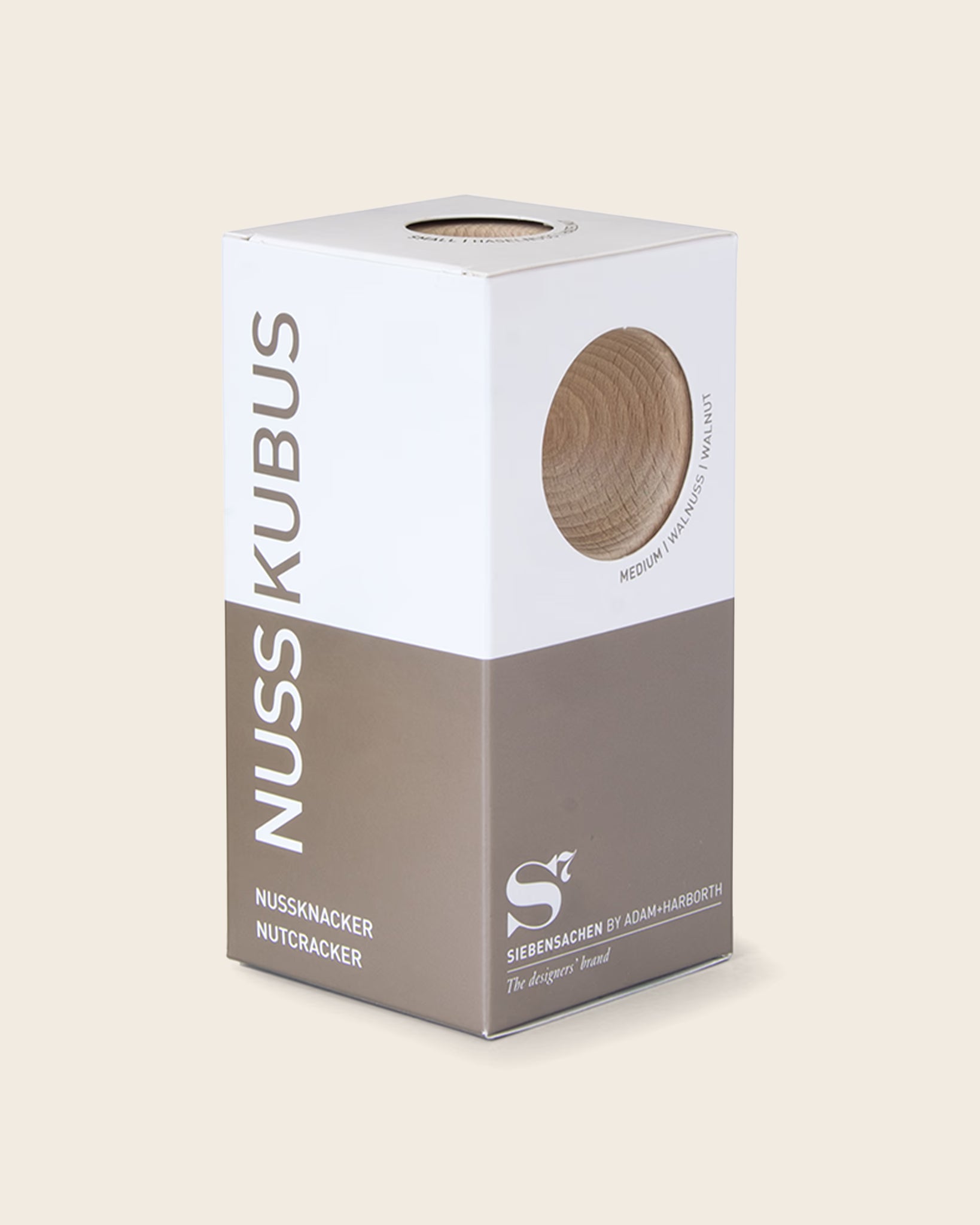 Verpackung des Nussknackers NUSSKUBUS von Siebensachen mit Sichtfenster, das das Buchenholz zeigt. Hochwertige Box in Weiß und Braun mit modernem Design und klarer Typografie.
