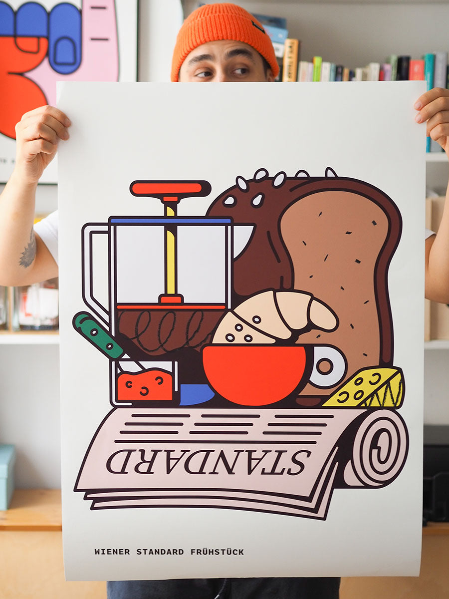Illustration eines Wiener Standardfrühstücks mit Kaffeepresse, Kaffeetasse, Kipferl, Brot, Käse und Zeitung. Die Zeitung trägt den Schriftzug „STANDARD“, darunter steht „Wiener Standard Frühstück“. Die Darstellung ist grafisch, farbig und stilisiert. Das Poster wird von Johann, Teil des DesignDuos RadandYellow gehalten.