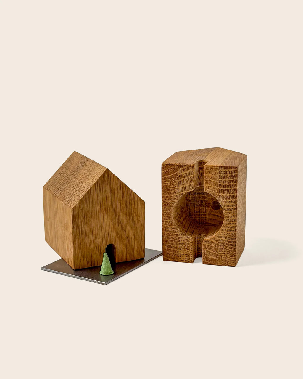 Holzräucherhäuschen aus recyceltem Eichenholz mit kleiner Türöffnung, daneben ein tannengrüner Räucherkegel auf einer Edelstahlplatte.