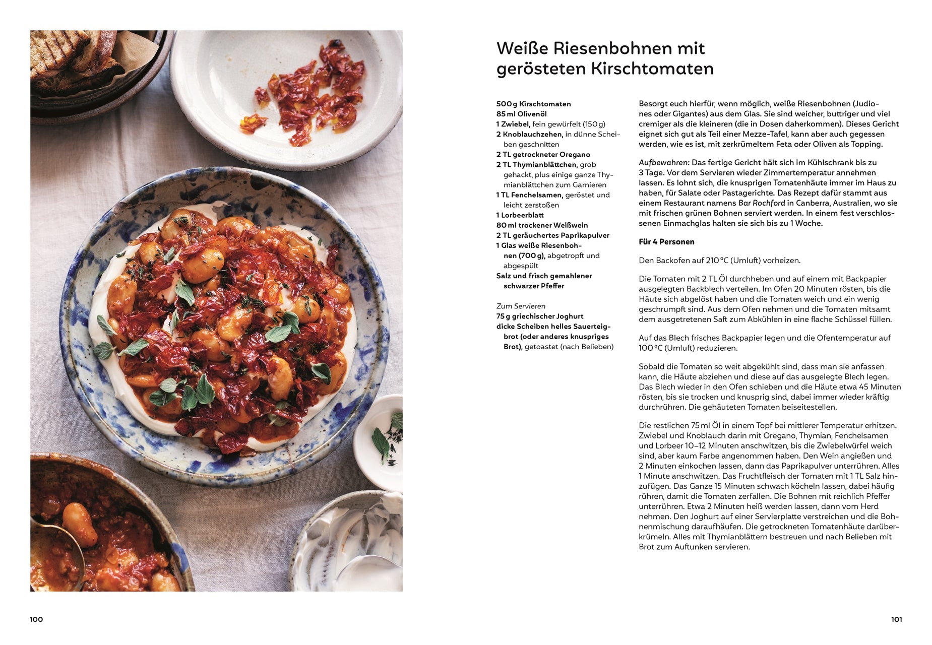 Weiße Riesenbohnen mit gerösteten Kirschtomaten: Schmortopf mit weißen Riesenbohnen in einer würzigen Tomatensauce auf Joghurt, dekoriert mit frischen Oreganoblättern, umgeben von leeren Schalen und angeröstetem Brot.