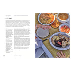 Cocido: Ein gedeckter Tisch mit verschiedenen Schüsseln voller Cocido-Zutaten: Kichererbsen, Gemüse, klare Brühe und Fleischstücke wie Huhn, Rind, Chorizo und Morcilla. Eine Hand serviert gerade auf einem hellen Teller. Rustikale, familiäre Atmosphäre im Sonnenlicht.