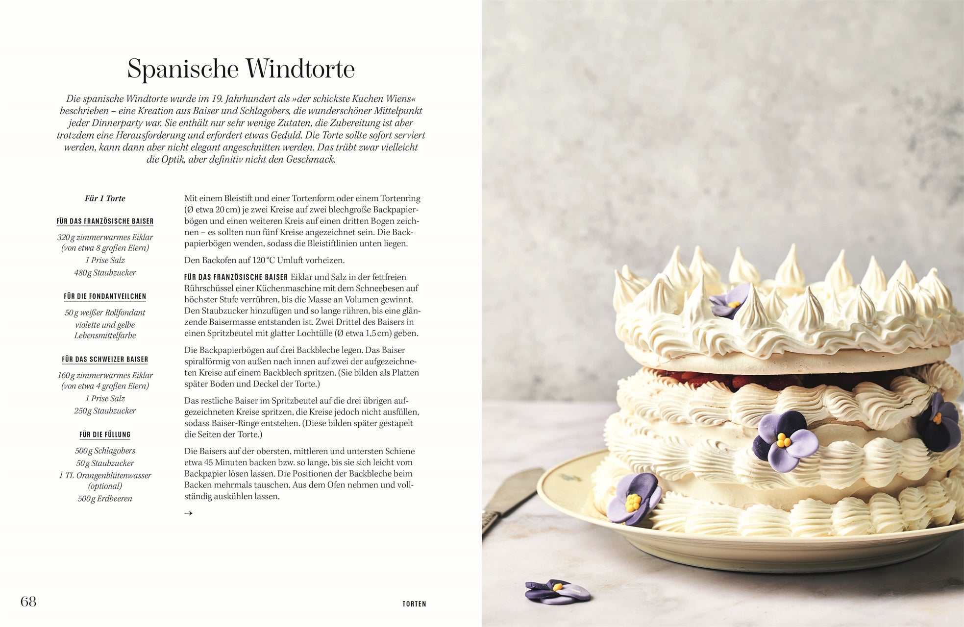 Rezept Spanische Windtorte: Große, kunstvoll verzierte Spanische Windtorte aus Baiser und Schlagobers, geschichtet mit dekorativen Tuffs und essbaren Blüten auf einer hellen Platte.