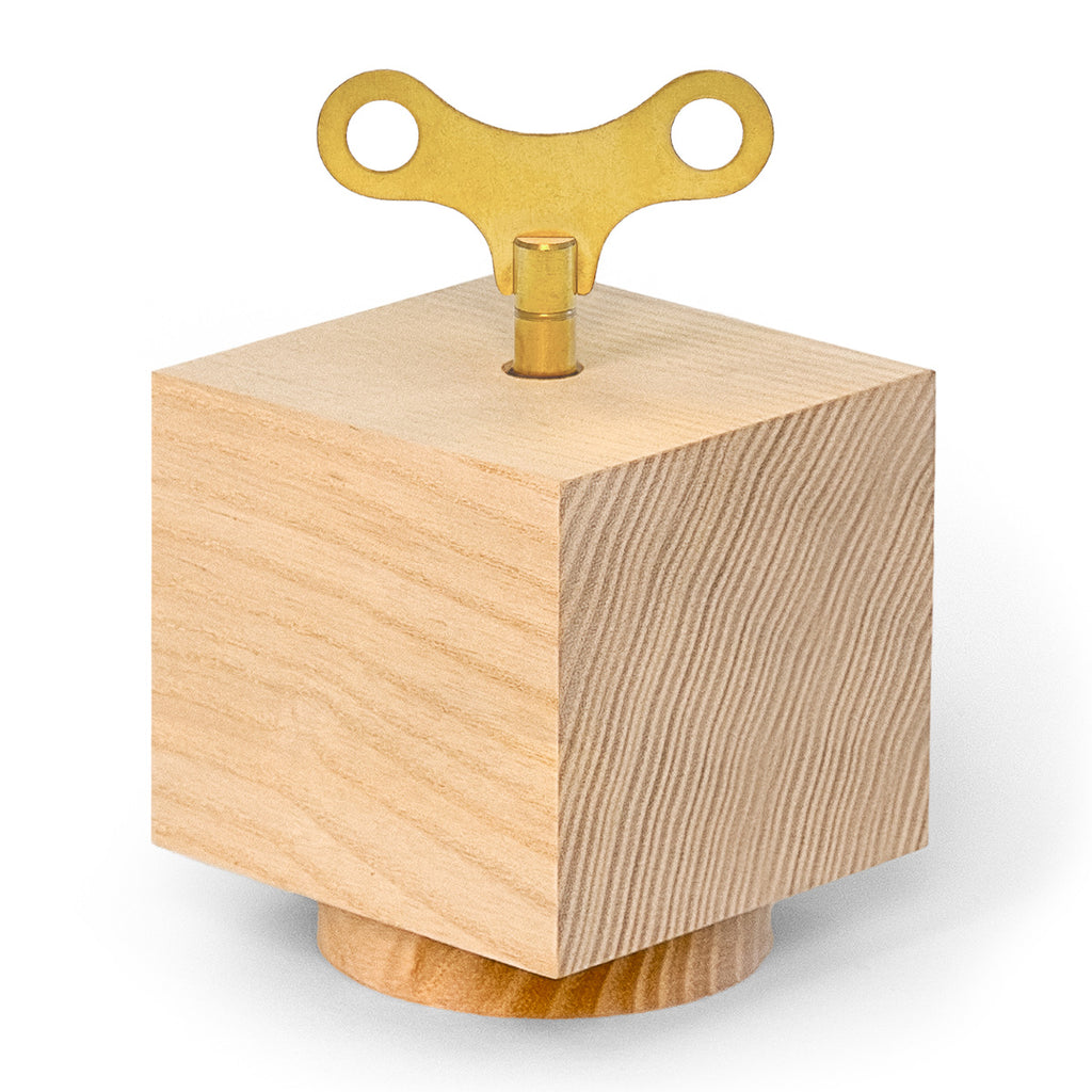 Spieluhr ‚Nature Spring‘ von Siebensachen aus naturbelassenem Eschenholz, kubisches Design mit goldenem Aufziehschlüssel.