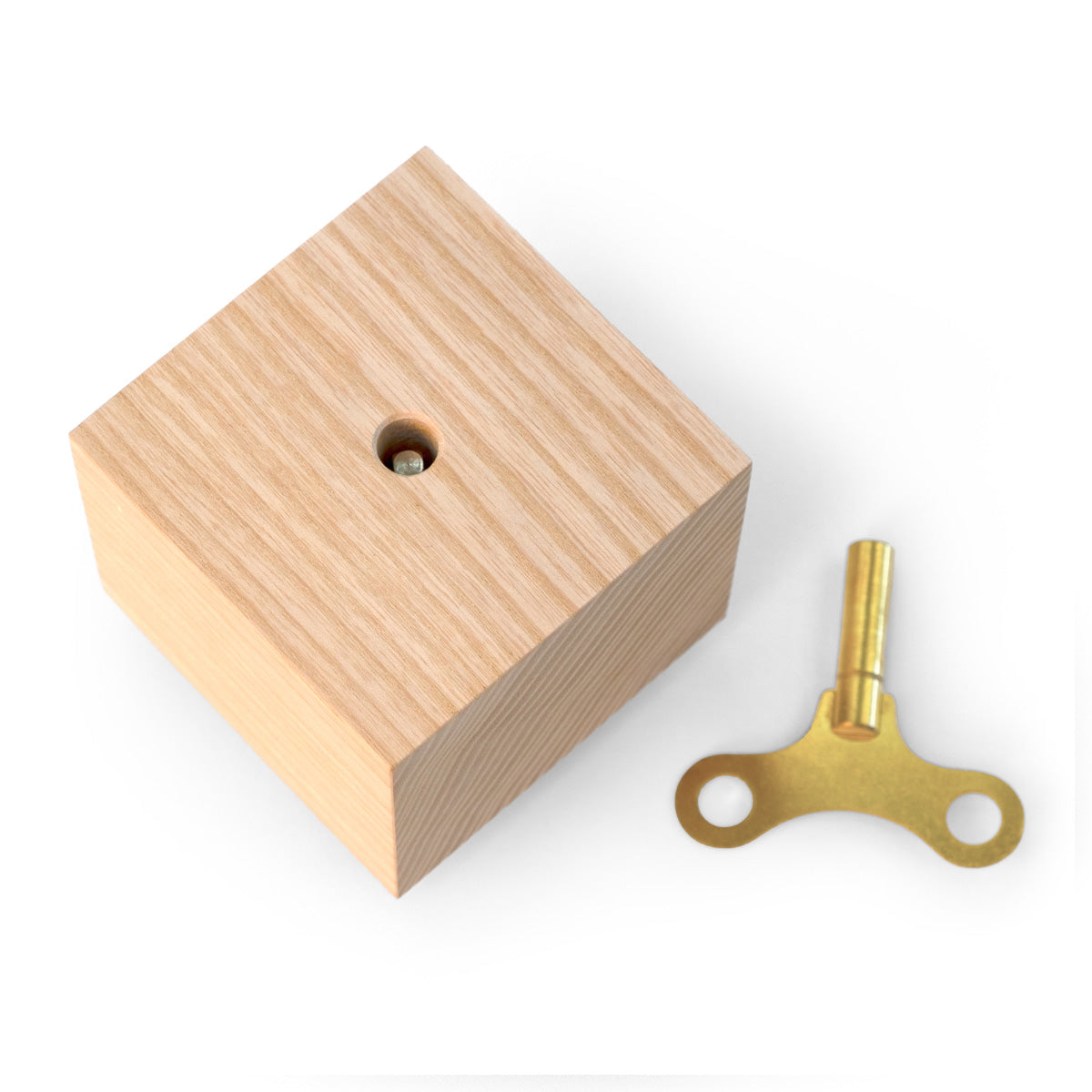 Spieluhr ‚Nature Spring‘ von Siebensachen: naturbelassener Eschenholz-Block mit sichtbarer Aufzugsöffnung und goldenem Aufziehschlüssel aus Metall.