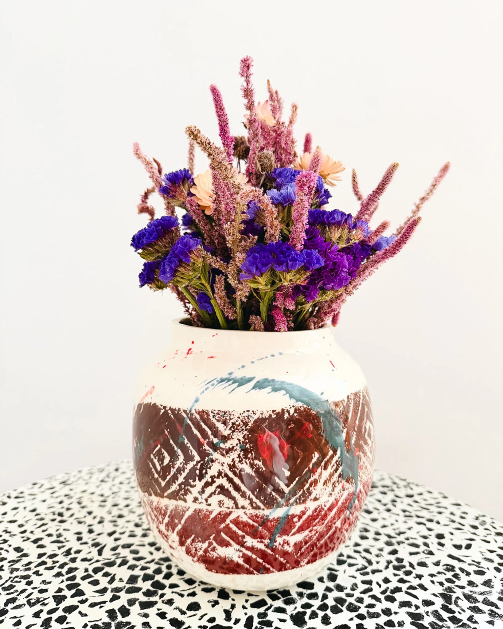 Femme Terre Vase von Mica Barbot mit Trockenblumenarrangement. Die handgefertigte Steingutvase aus Nizza vereint natürliche Erdtöne mit künstlerischen Farbverläufen in Blau und Rot. Ihre strukturierte Oberfläche und organische Form machen sie zu einem ausdrucksstarken Dekorationsobjekt, das jedem Raum mediterranes Flair und künstlerische Tiefe verleiht.