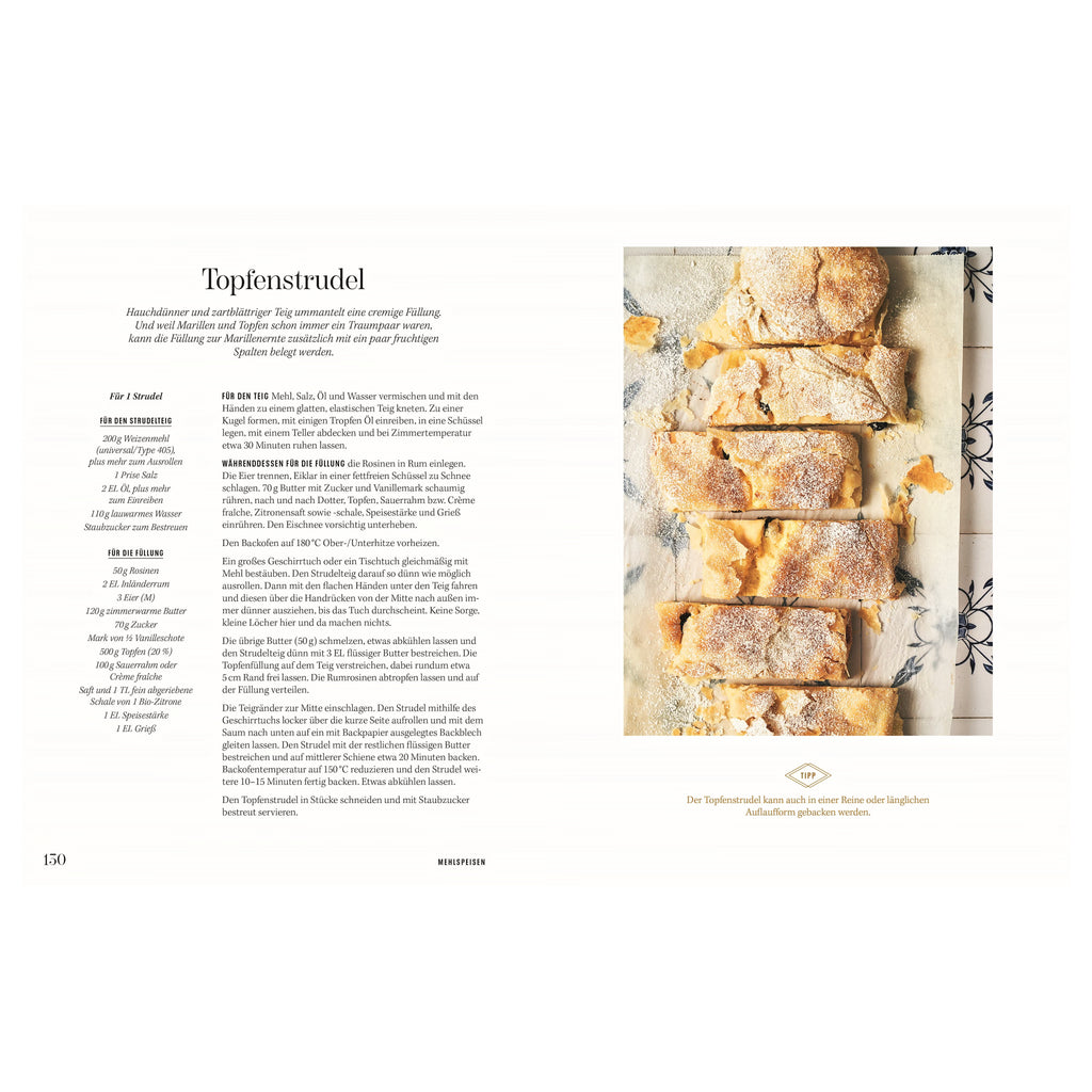 Rezept Topfenstrudel: Frisch gebackener Topfenstrudel auf Backpapier, in Stücke geschnitten, mit Staubzucker bestäubt; rustikale Optik auf gefliester Unterlage.