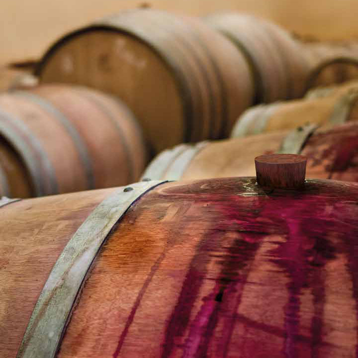 Nahaufnahme von Barriquefässern mit tiefroten Weinflecken auf Eichenholz Symbolbild für Barrique Kugelschreiber von e + m aus echtem Weinfass Holz