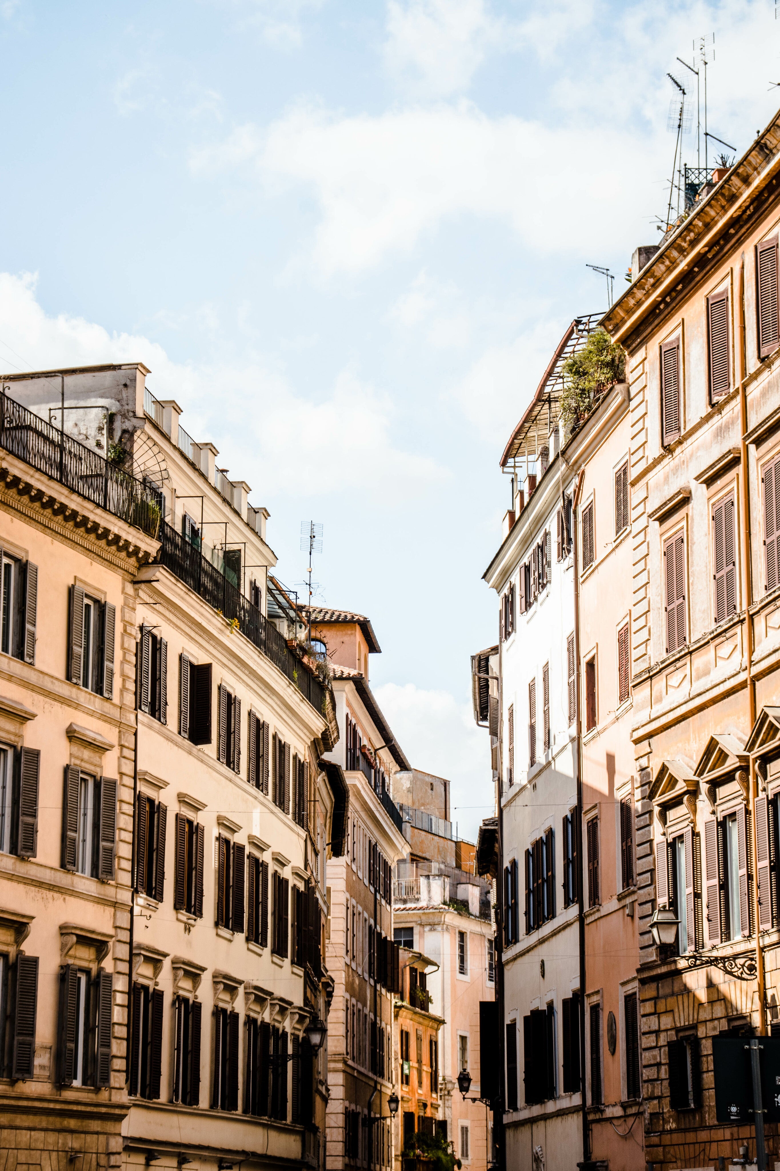 Sonnige europäische Altstadtstraße mit historischen Häuserfassaden und geöffneten Fensterläden.