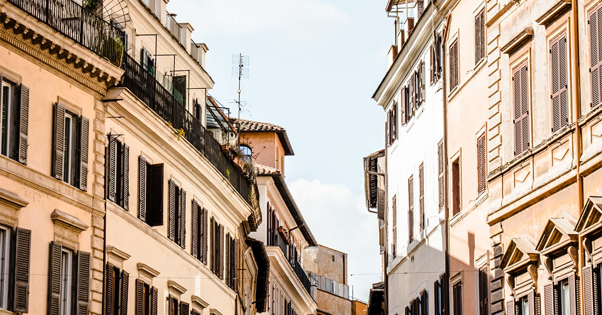 Sonnige europäische Altstadtstraße mit historischen Häuserfassaden und geöffneten Fensterläden.