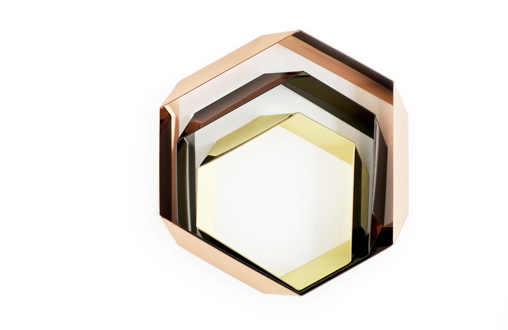 Design-Untersetzer-Set HEXAGON von Siebensachen, bestehend aus drei hexagonalen Elementen in den Farben Messing, Kupfer und Gold. Die glänzenden, polierten Metallbänder lassen sich dekorativ ineinanderlegen und bilden eine elegante, florale Tischskulptur. Teil der A+H Foreign Affairs Reihe.