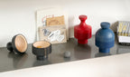 Design objects ANUKI HINTO and DEVAKI by NIEVEN displayed on a shelf in red blue and black hand-turned ash wood bowls modern home accessories for storage and decoration made in Germany.