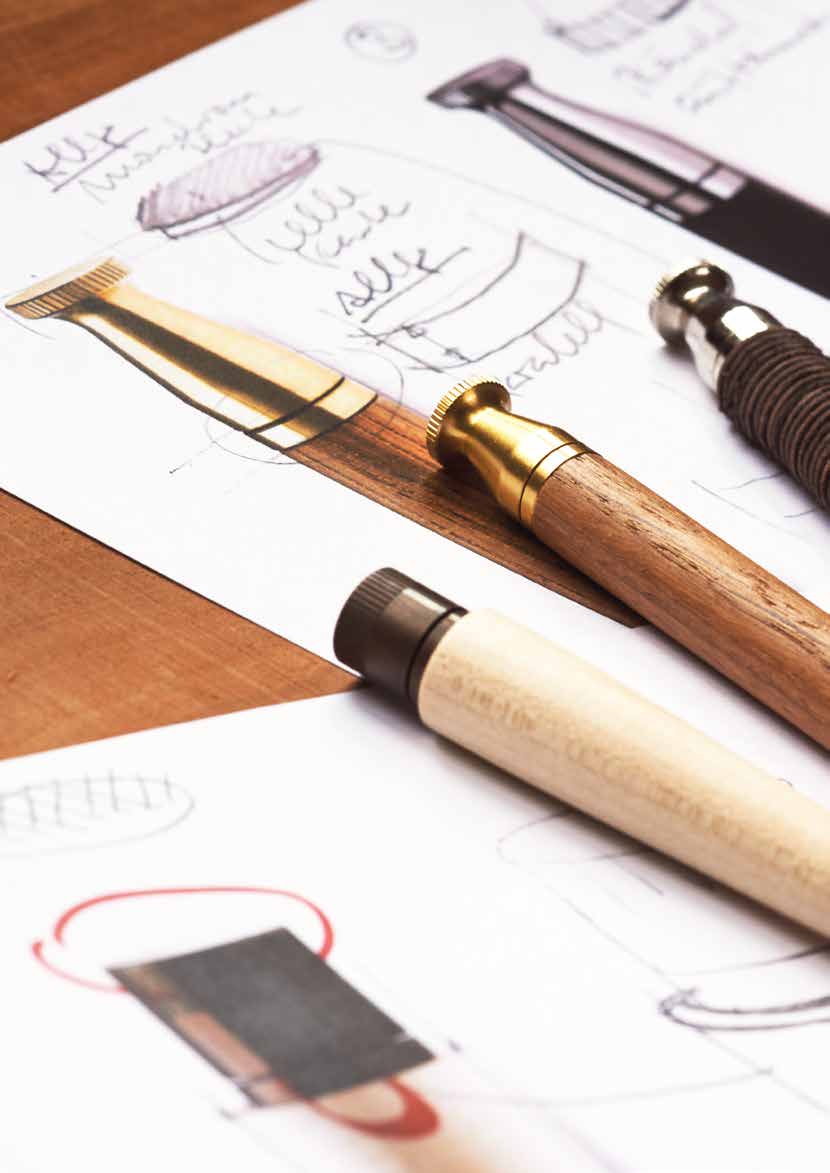 Designskizzen und Prototypen von hochwertigen Holzkugelschreibern auf einem Schreibtisch zeigen den kreativen Entwurfsprozess und die handwerkliche Präzision von e+m.