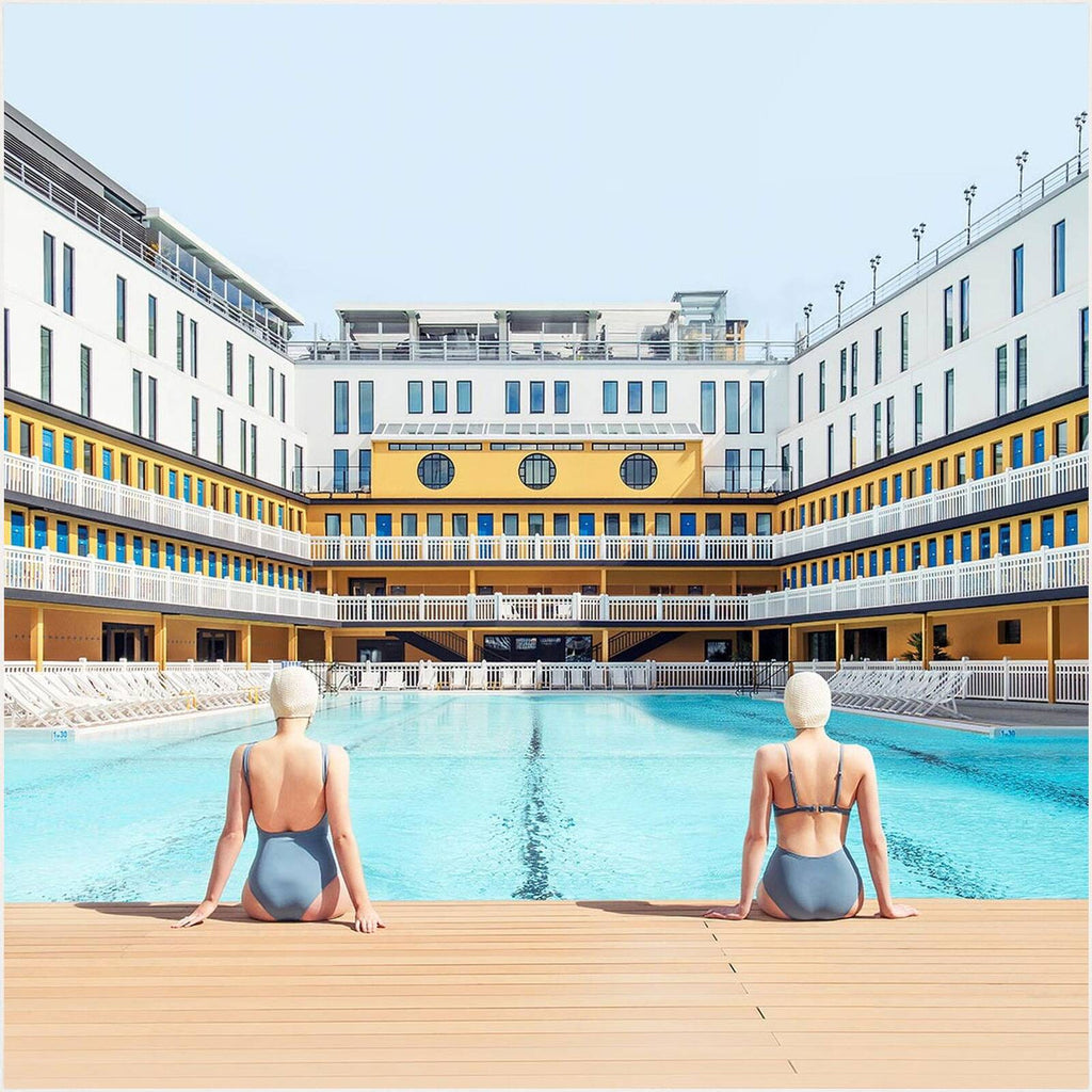 Fotokunstwerk Summer Swim at Molitor von Soo Burnell aus der Serie Into the Blue, zeigt zwei Frauen in Badeanzügen am Pool des legendären Hôtel Molitor in Paris, inspiriert von der Ästhetik Wes Andersons.