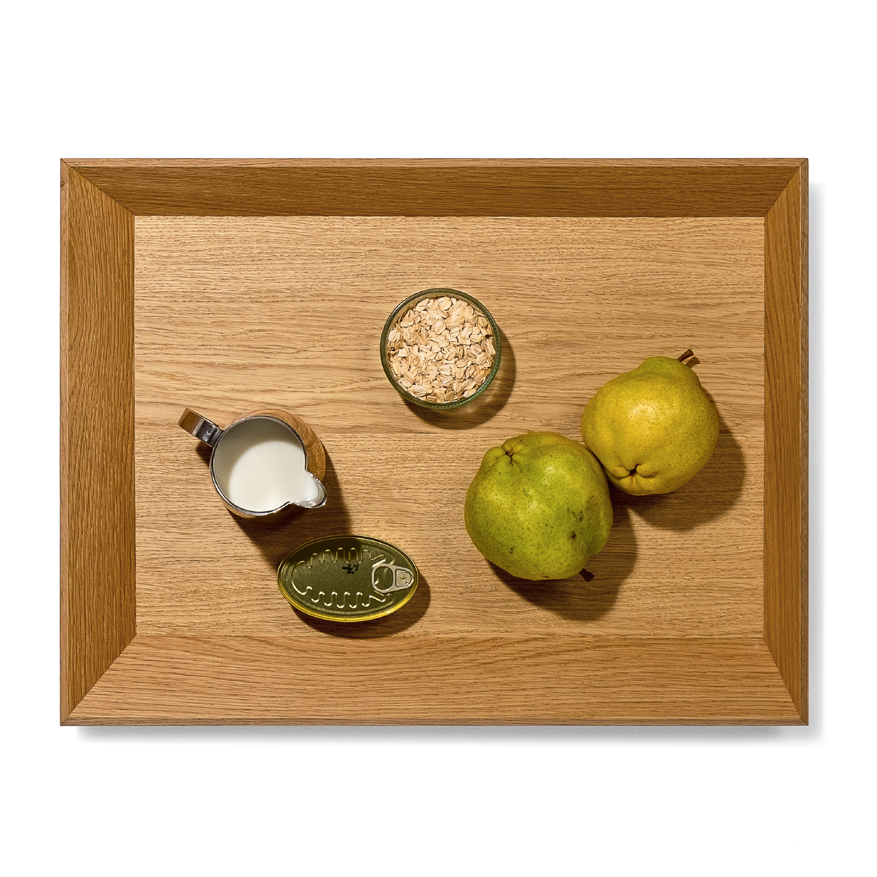 Wooden tray OBLIQUE by NIEVEN with architectural design. Rectangular oak tray with beveled edges arranged with milk, oats, a tin and two quinces. Design by Jörg Adam.