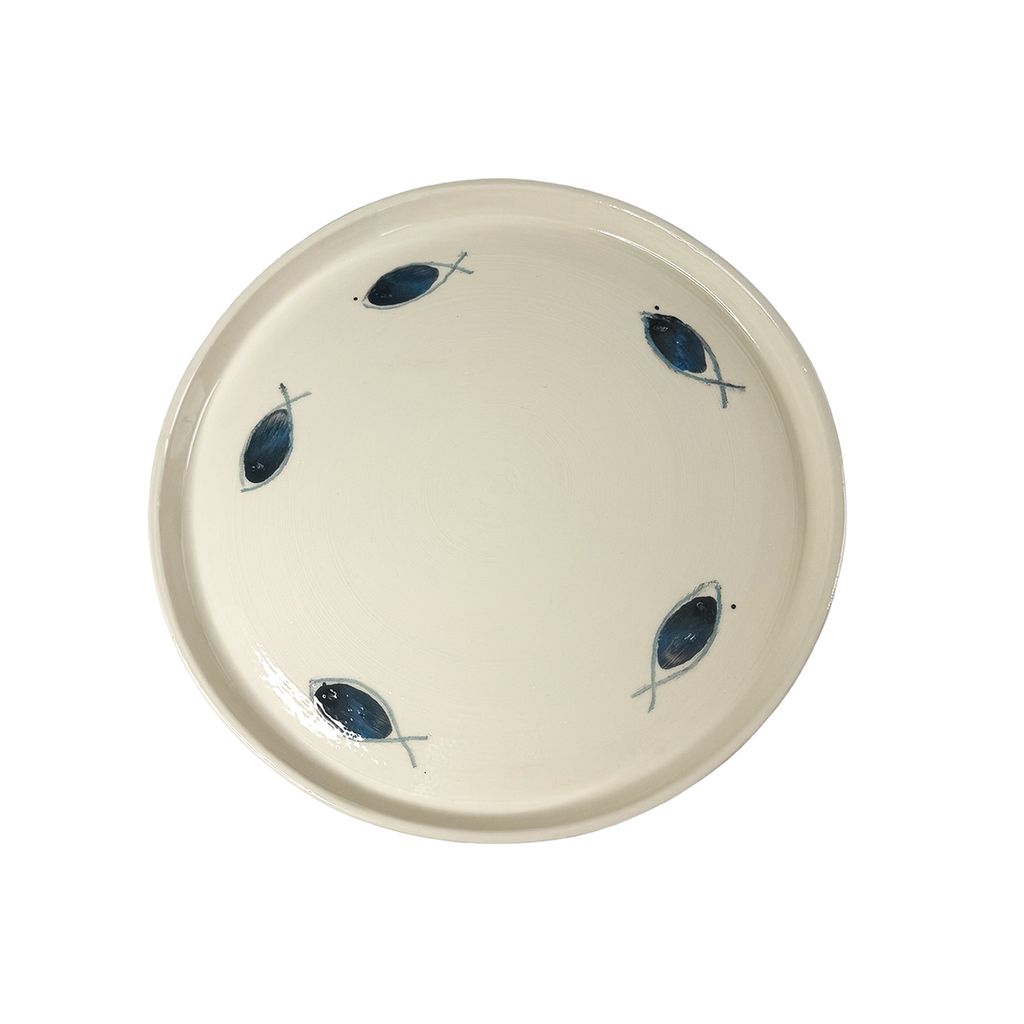Handgefertigter Keramikteller mit fünf blauen Fischmotiven von Mica Barbot aus Nizza. Der Teller wurde aus Steingut in der traditionellen Terres Vernissées-Technik gefertigt und von Hand bemalt. Seine minimalistische Gestaltung mit mediterranem Flair macht ihn zu einem besonderen Einzelstück für jede Tischdekoration.