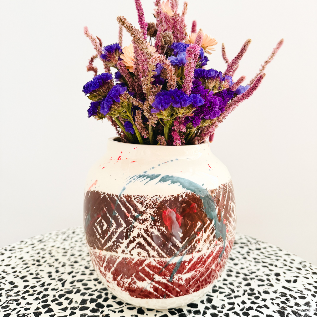 Femme Terre Vase von Mica Barbot mit Trockenblumenarrangement. Die handgefertigte Steingutvase aus Nizza vereint natürliche Erdtöne mit künstlerischen Farbverläufen in Blau und Rot. Ihre strukturierte Oberfläche und organische Form machen sie zu einem ausdrucksstarken Dekorationsobjekt, das jedem Raum mediterranes Flair und künstlerische Tiefe verleiht.