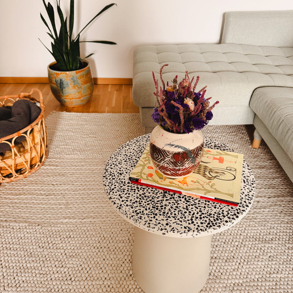 Femme Terre Vase von Mica Barbot als Wohnaccessoire in einem modernen Wohnzimmer. Die handgefertigte Steingutvase aus Nizza verleiht dem Raum mit ihren künstlerischen Mustern und mediterranen Farben einen warmen, kreativen Akzent. Perfekt als dekoratives Highlight auf Couchtischen oder Sideboards für ein stilvolles Zuhause mit Persönlichkeit.