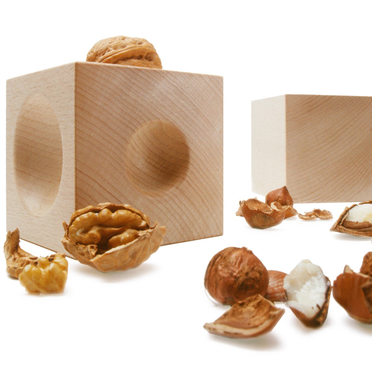 Nussknacker NUSSKUBUS von Siebensachen aus massivem Buchenholz mit gedrechselten Mulden, umgeben von geöffneten Walnüssen und Haselnüssen. Zeitloses Designobjekt, das Funktionalität und Ästhetik auf natürliche Weise verbindet.