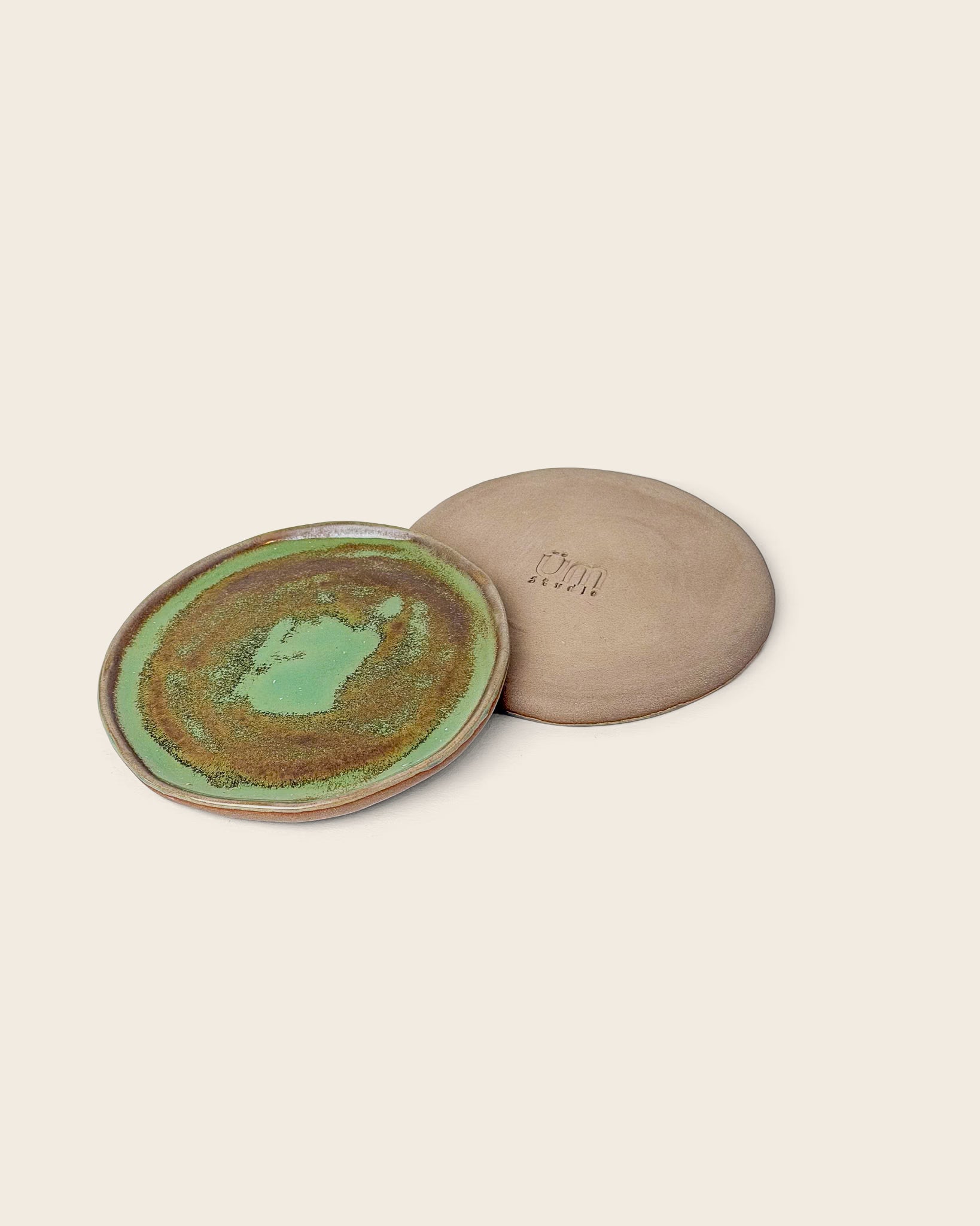 Handgefertigte Keramik-Tapasteller von Üm Studio in warmem Green-Tea-Glasurton mit natürlichen Braunnuancen. Kleine Steingut-Teller mit unregelmäßigem Rand, hergestellt in Málaga, Spanien. Perfekt als Tapasteller oder Untersetzer für ein modernes, authentisches Tischarrangement.