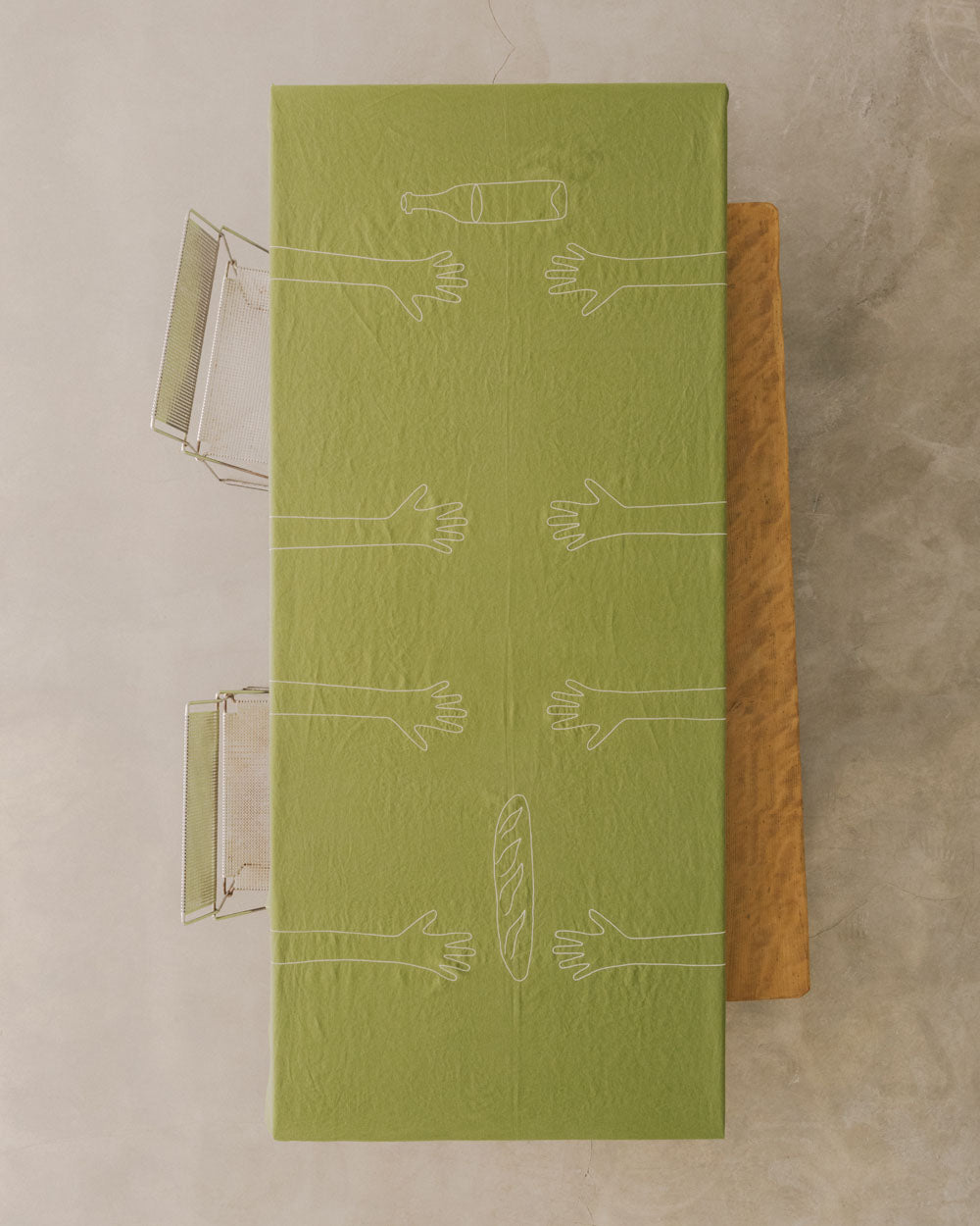 Handgestickte grüne Leinen-Tischdecke MAINS SUR LA TABLE von OEUVRES SENSIBLES. Französisches Design mit gestickten Händen, Baguette und Weinflasche – 100 % Leinen, gefertigt in Frankreich. Bild © Maxime Verret