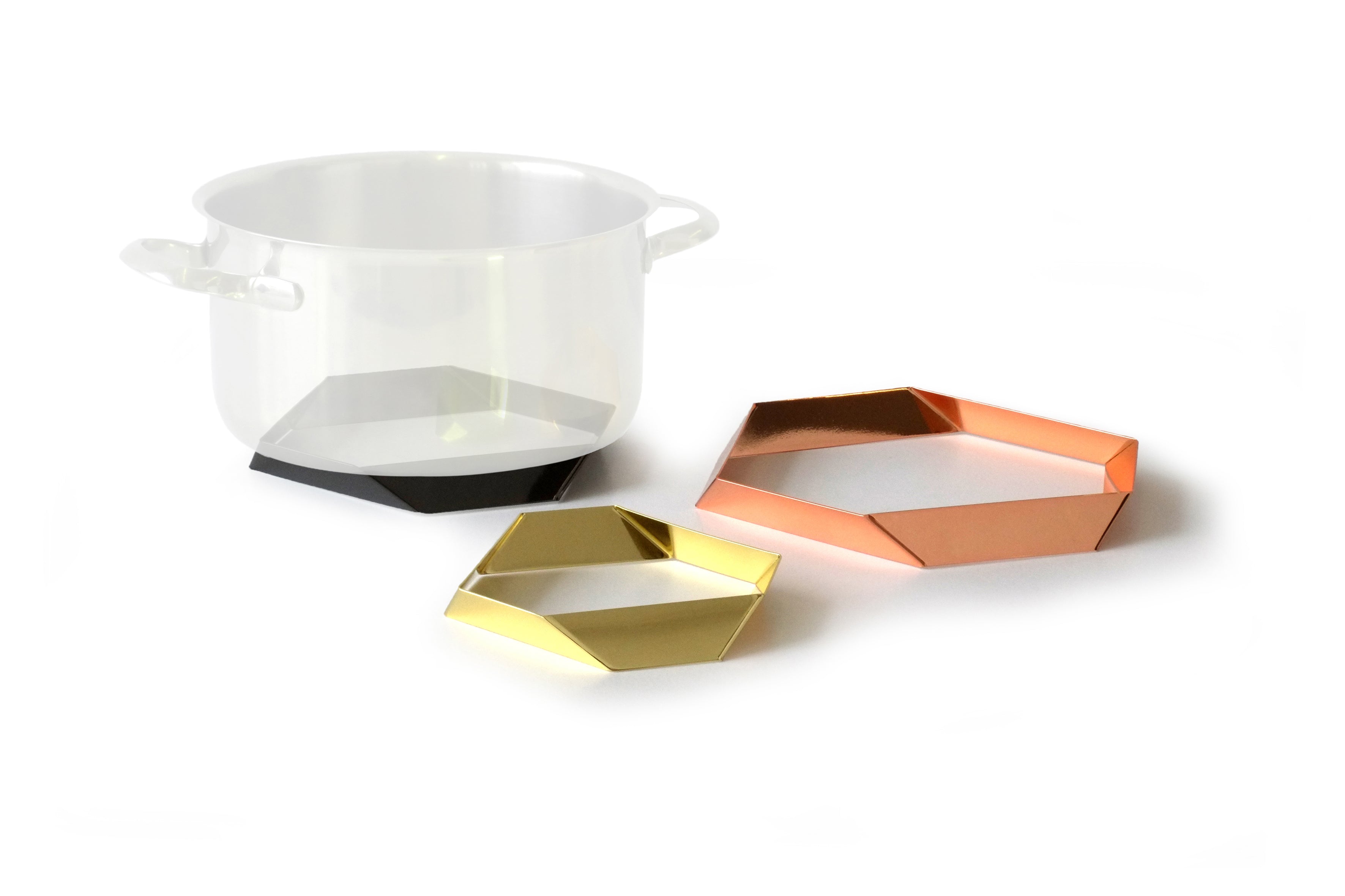 Design-Untersetzer-Set HEXAGON von Siebensachen aus polierten Metallbändern. Glänzt in den Farben Messing, Kupfer und Gold. Die prismatischen Elemente dienen als stilvolle Topfuntersetzer und lassen sich zu einer dekorativen Tischskulptur arrangieren. Teil der A+H Foreign Affairs Reihe.